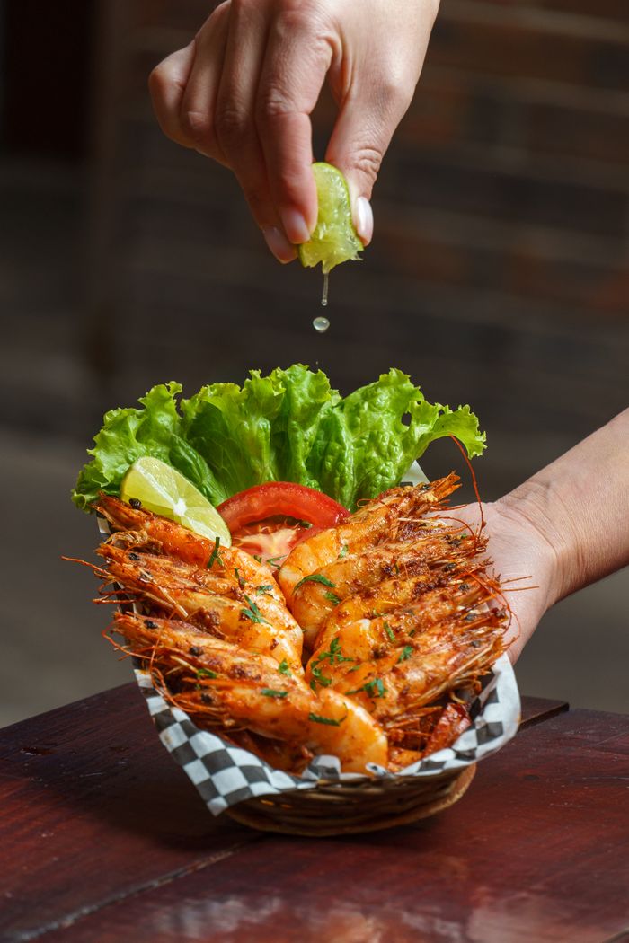 gallery-5 Delicious grilled shrimp garnished with lime and fresh lettuce, perfect for a seafood meal.