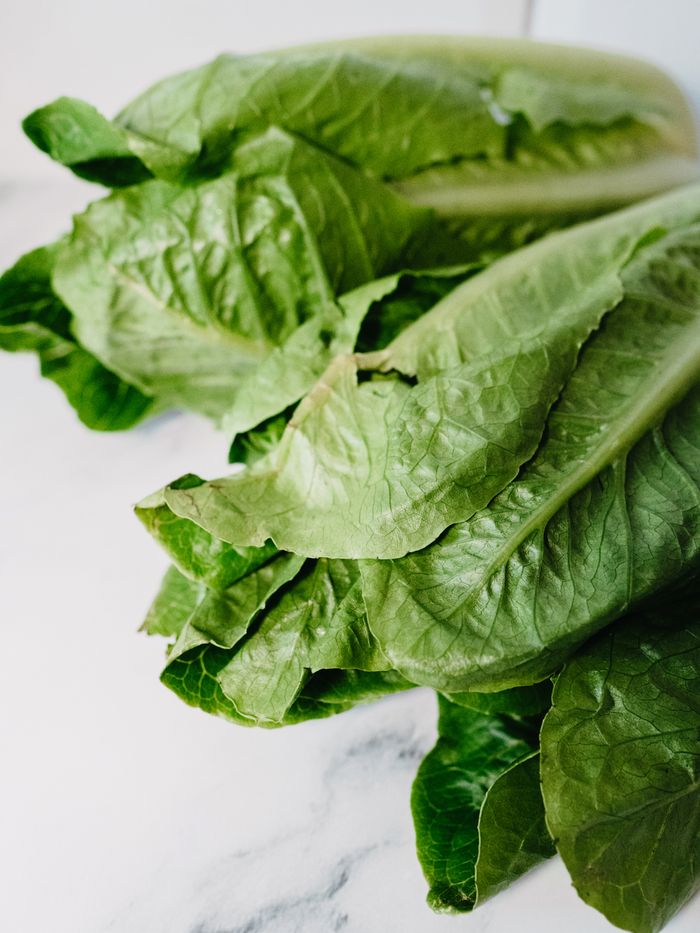 Close-up of fresh green romaine lettuce leaves on a marble countertop, perfect for salads.