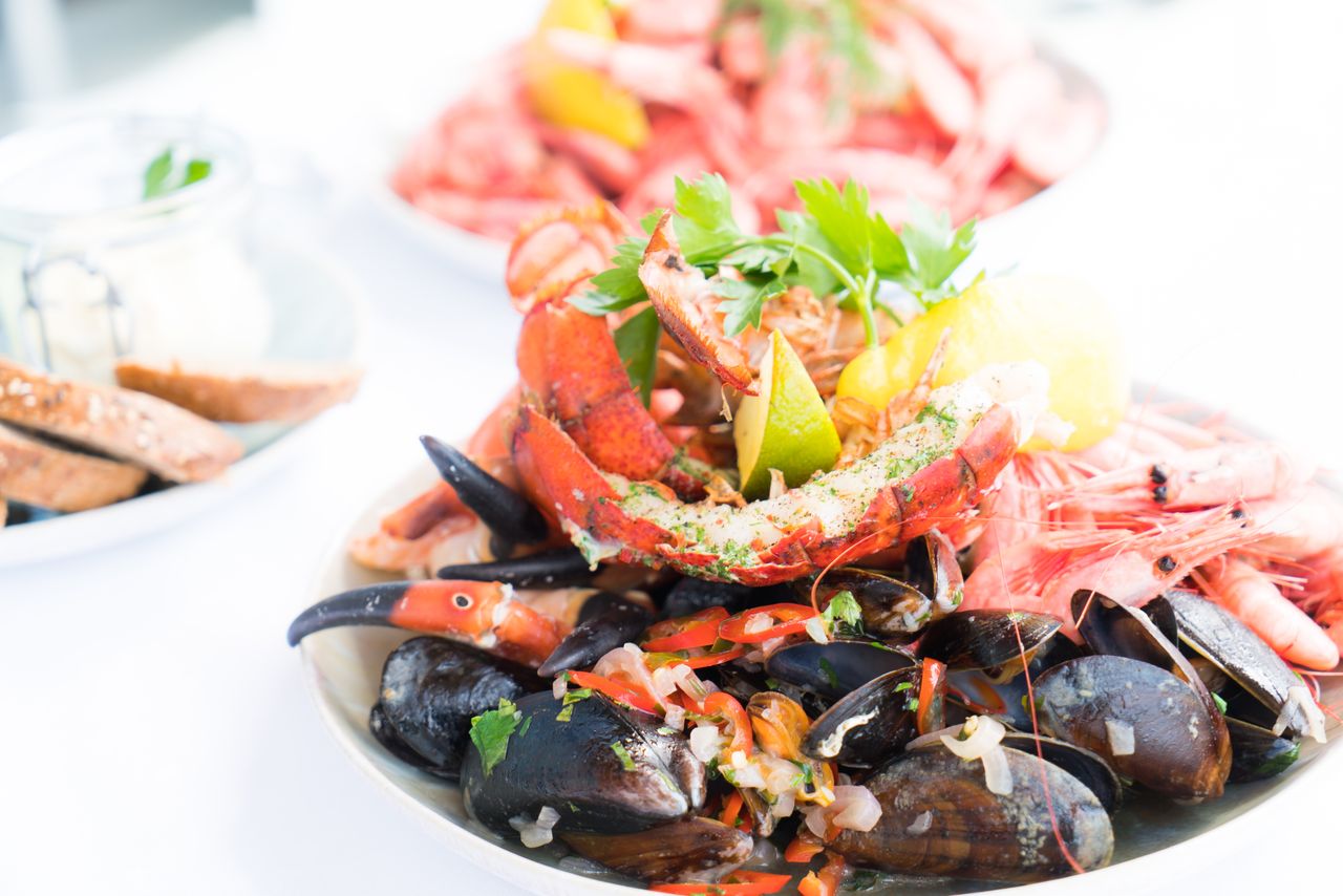 gallery-1 A vibrant seafood platter featuring lobster, mussels, and shrimp, garnished with herbs and lemon.