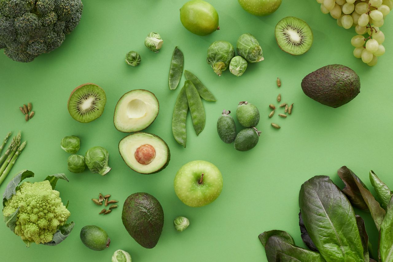 about-01 A variety of fresh green fruits and vegetables on a matching background, showcasing healthy organic produce.