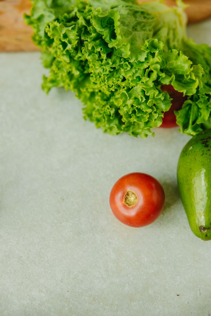 why-choose-us Close-up of fresh avocado, tomato, and lettuce on a white surface.